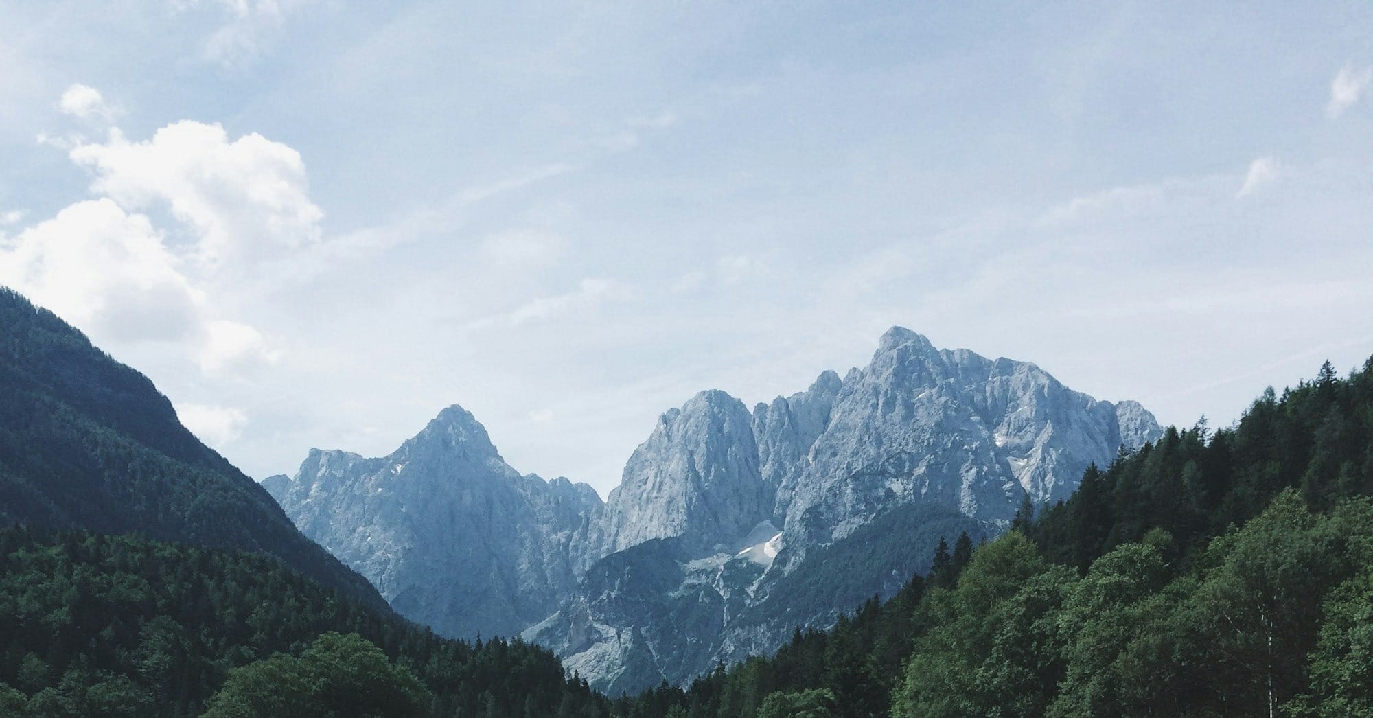 calm body of water surrounded with trees and mountain